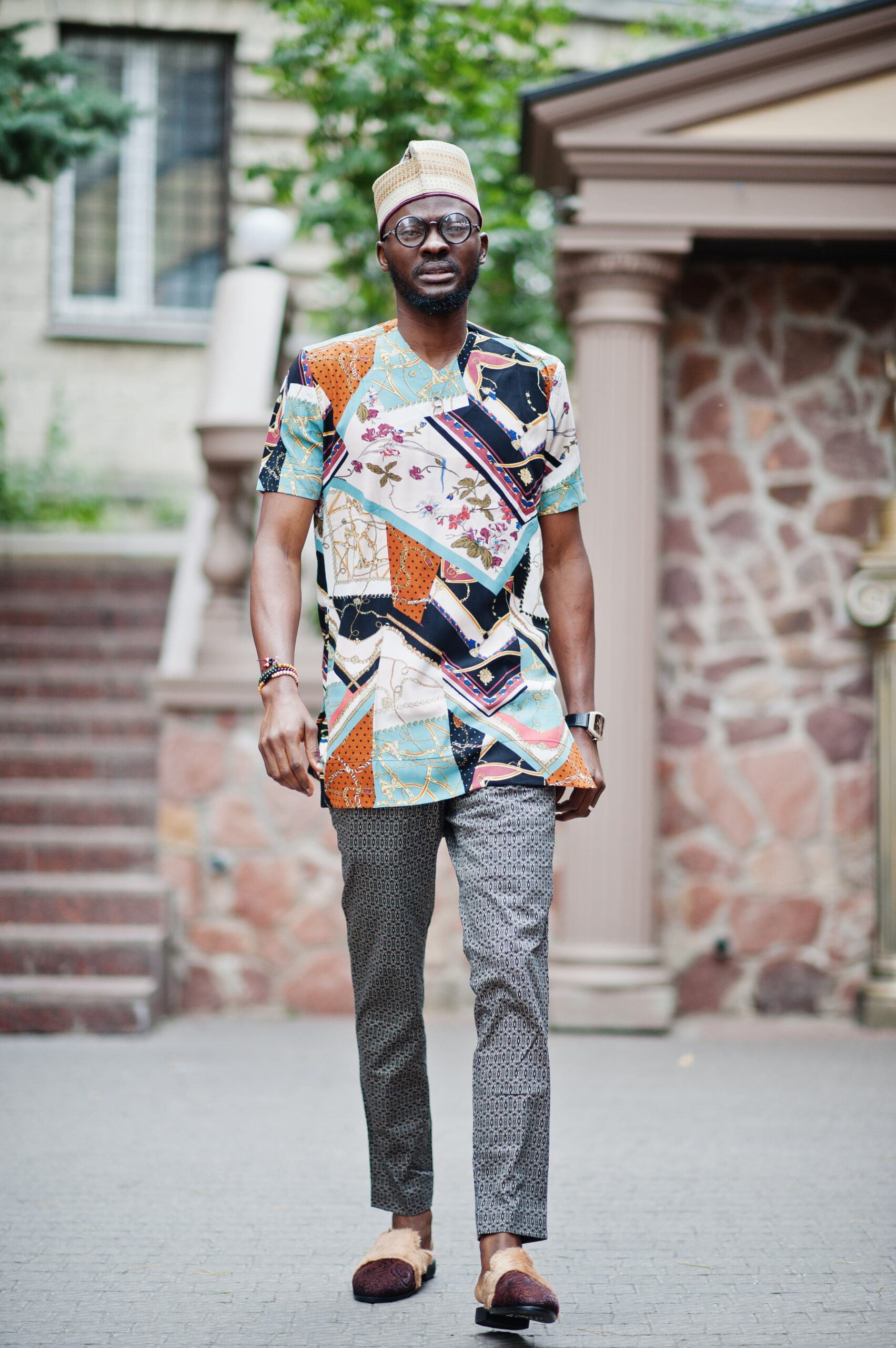 Handsome afro american man wearing traditional clothes, cap and eyeglasses in modern city.